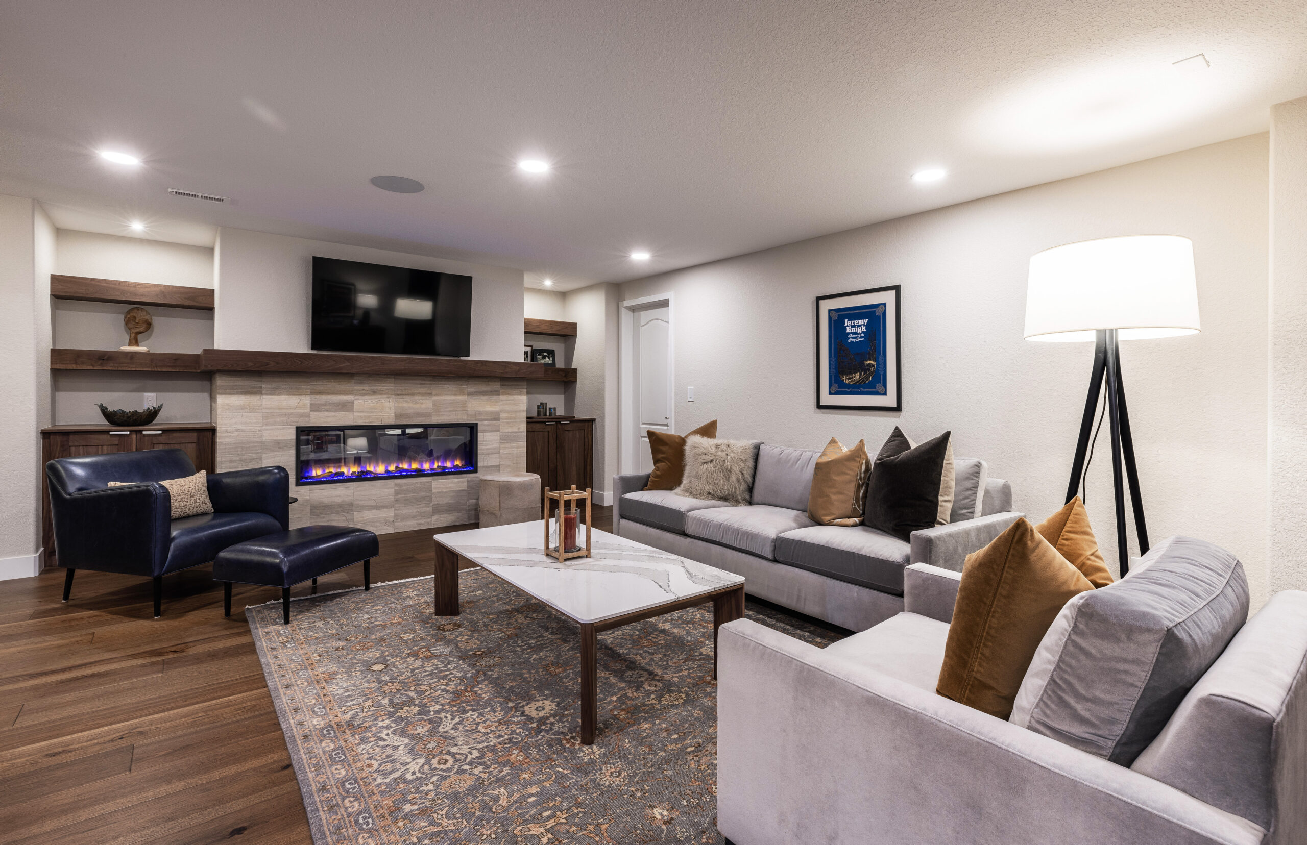 Cozy basement living room with a fireplace, large sectional sofa, armchair, and a TV, illustrating a comfortable and stylish space.